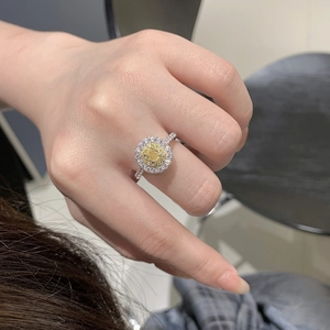 Top view of a silver halo ring with a round yellow gemstone and pavé diamonds