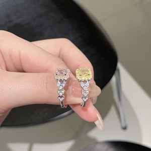 Détail de bagues carrées roses et jaunes avec anneaux en argent sertis de cœurs