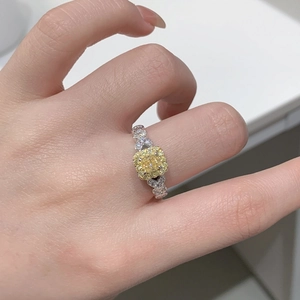 Detail of square yellow diamond ring on hand with heart-shaped silver band accents