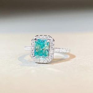 Radiant cut mint green moissanite ring with halo setting and pave band in silver finish