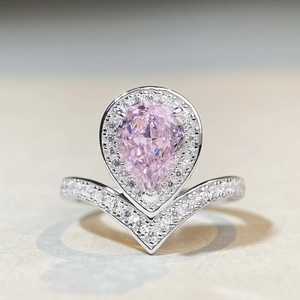 Macro shot of pear-shaped pink gemstone ring with halo diamonds and V-shaped band