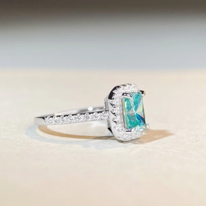 Radiant cut mint green moissanite ring in silver with halo diamonds and side stones