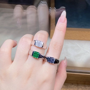 Detailed view of silver rings featuring square-cut emerald and sapphire gemstones on hand