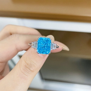 Macro shot of 925 silver ring featuring radiant cut blue stone and trapezoid side diamonds