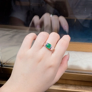 Macro detail of emerald cut green gemstone ring in silver finish on a model hand