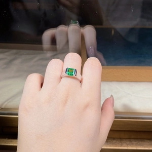 Detailed view of square emerald cut green gemstone on a wide polished silver band
