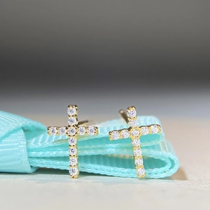 Vue macro de boucles d'oreilles croix dorées serties de pierres moissanite brillantes
