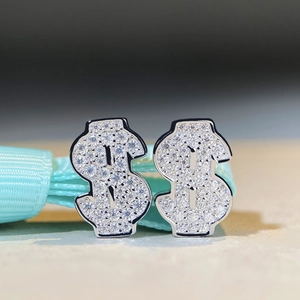 Détail macro de boucles d'oreilles signe dollar en argent S925 avec pierres moissanites