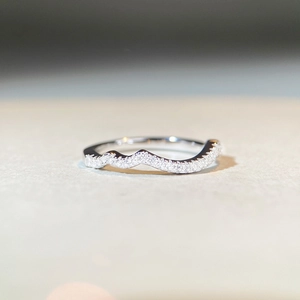 Macro shot of silver S925 stacking ring with a wavy zircon-encrusted curved design