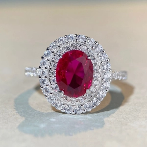 Détail macro d'une bague rubis ovale avec double halo et pavé de diamants en argent