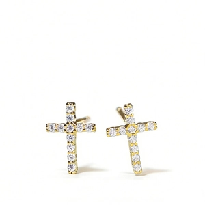 Élégantes boucles d'oreilles croix dorées serties de pierres sur fond blanc