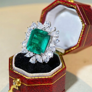 Vintage emerald-cut green gemstone ring with white floral zircon halo in a red jewelry box
