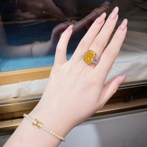 Dettaglio anello in moissanite taglio cushion giallo e set bracciale tennis oro