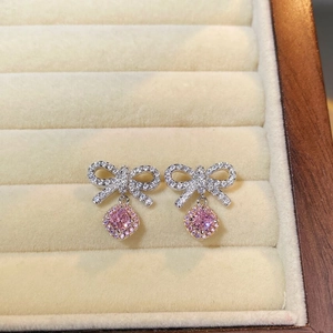 Macro shot of 925 silver bow earrings with pink square zircon pendant on velvet display