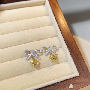 Detailed close-up of S925 silver bow earrings with yellow halo cushion-cut gemstones
