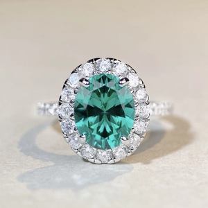 Vue macro d'une bague ovale en pierre verte avec halo de diamants et anneau en argent