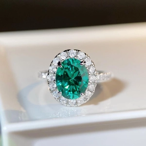 Vue macro d'une bague avec pierre verte ovale et sertissage halo en argent et diamants