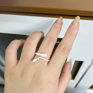 Detail view of a silver snake-shaped ring with textured scales and pink diamond eyes