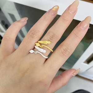 Dettaglio di anelli a serpente in oro e argento con squame e pietre rosa agli occhi