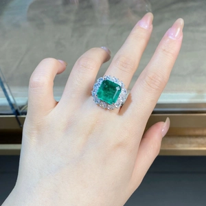 Macro detail of silver ring with emerald-cut green stone and sparkling side diamonds