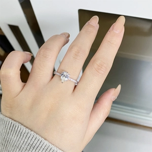 Pear cut moissanite engagement ring in 925 silver worn on hand with a paved band