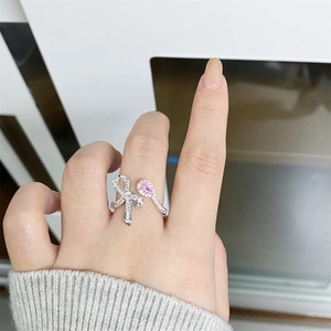 Close-up of S925 silver bow ring with pink pear-cut stone and pavé diamonds on hand