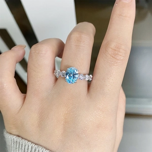 Close-up of S925 silver ring with oval sky blue aquamarine and side diamonds on finger