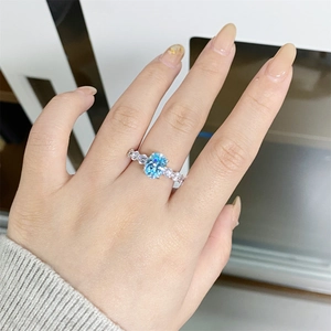 Macro shot of silver ring featuring oval blue aquamarine stone on a model hand