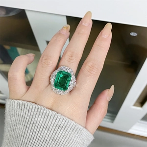 Macro shot of an emerald-cut green gemstone ring with double halo sparkling diamonds
