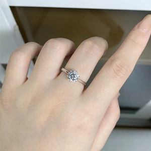 Detailed close-up of a classic six-prong silver engagement ring on a woman's hand