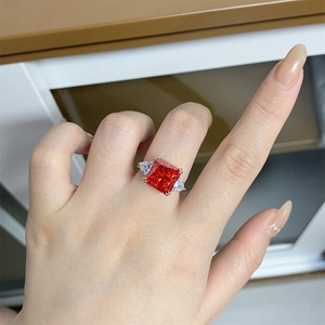 Detailed view of radiant cut 5-carat ruby ring with trillion side stones on hand