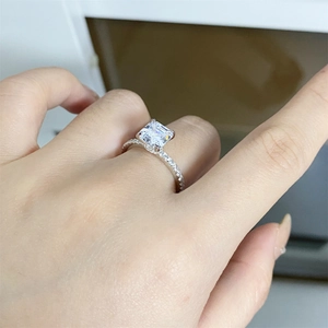 Detail of princess cut moissanite ring with four-prong setting and pavé silver band