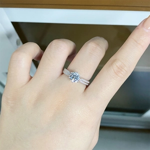 Close-up of a 1 carat round moissanite ring with side accent diamonds on silver band