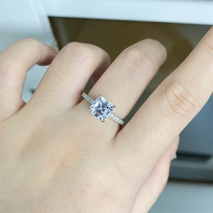 Macro shot of 2-carat Asscher cut moissanite ring with side stones on a finger