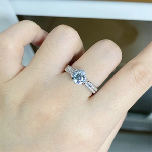Close-up of a 1 carat moissanite ring with six-prong setting and side diamonds on finger