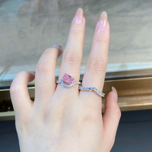Detail of pink radiant cut diamond ring set with wavy pave bands on finger