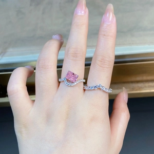 Close-up of a stacked sterling silver ring set with a radiant cut pink stone on a finger
