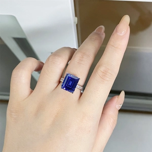 Macro view of emerald-cut blue gemstone ring set in silver with side stone accents