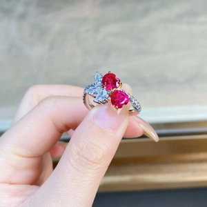 Close-up of dual red heart-shaped gemstones on a polished silver band with white diamonds