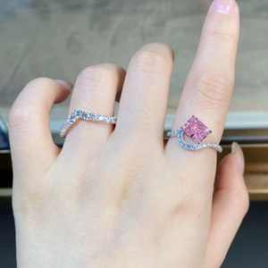 Close-up of radiant cut pink stone ring stacked with V-shaped silver pavé band