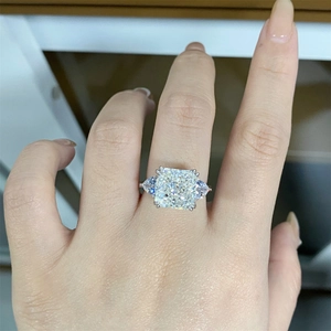 Close-up of cushion cut silver ring featuring side pear diamonds on a female finger