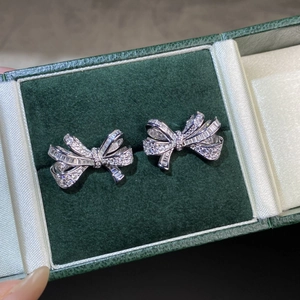Macro shot of silver bow earrings with sparkling pavé crystals in a green velvet box