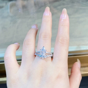 Macro shot of S925 silver pear-cut diamond ring set with V-shaped pavé band on finger