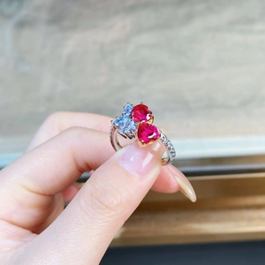 Macro detail of silver ring featuring red heart-shaped gems and blue marquise stones