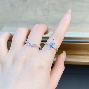 Close-up of stacked S925 sterling silver marquise cut rings and V-shaped band on finger