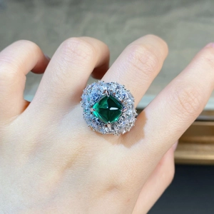 Vue macro d'une bague avec pierre verte taille émeraude et pavage de diamants blancs