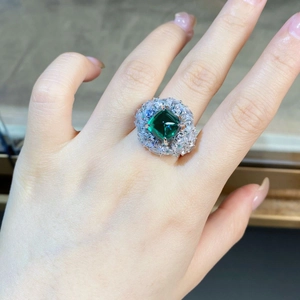 Gros plan sur une bague luxe vert émeraude avec halo de diamants marquise et ronds
