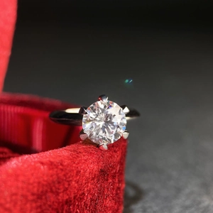 Macro shot of a classic six-prong moissanite ring set on a luxurious red velvet box