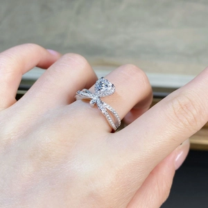 Macro shot of a heart-shaped Moissanite ring with a diamond crossover halo band