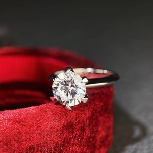 Close-up of classic six-prong moissanite ring on red velvet jewelry box with depth of field